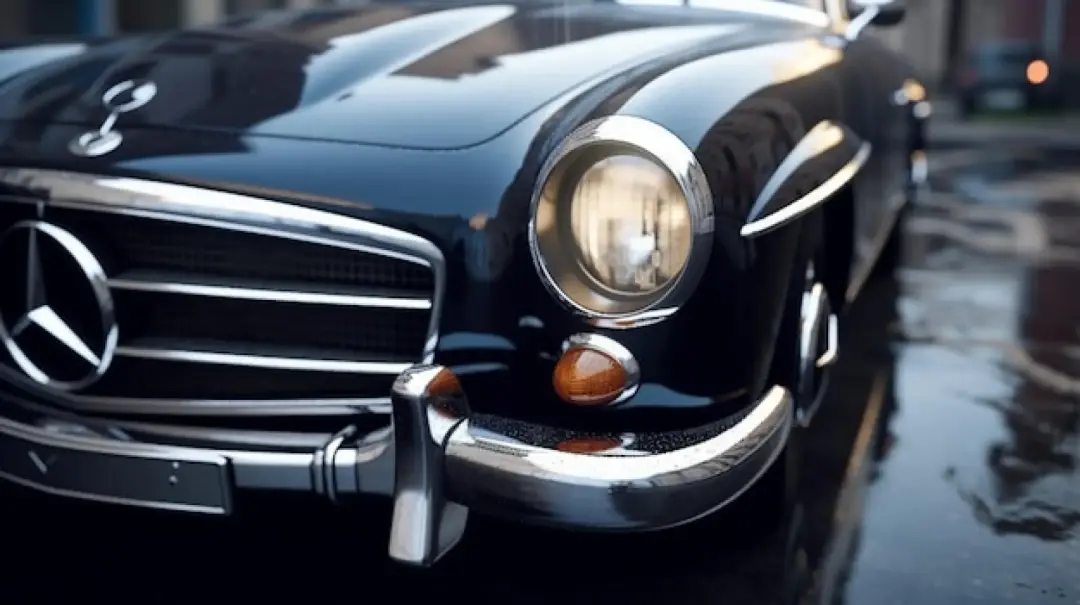 Front of a classic black Mercedes-Benz with round headlamps and a chrome grille, on a wet street